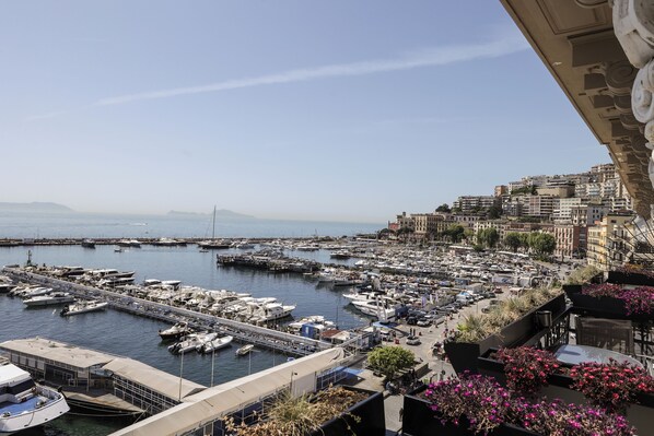A marina with numerous boats docked, a bridge connecting to the mainland, and a cityscape with buildings in the background. - Demetra Luxury Suites (Naples)