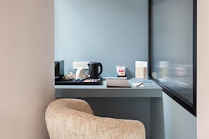 A corner workspace with a desk, a coffee maker, a bag of coffee, a notebook, and a chair. - Demetra Luxury Suites (Naples)