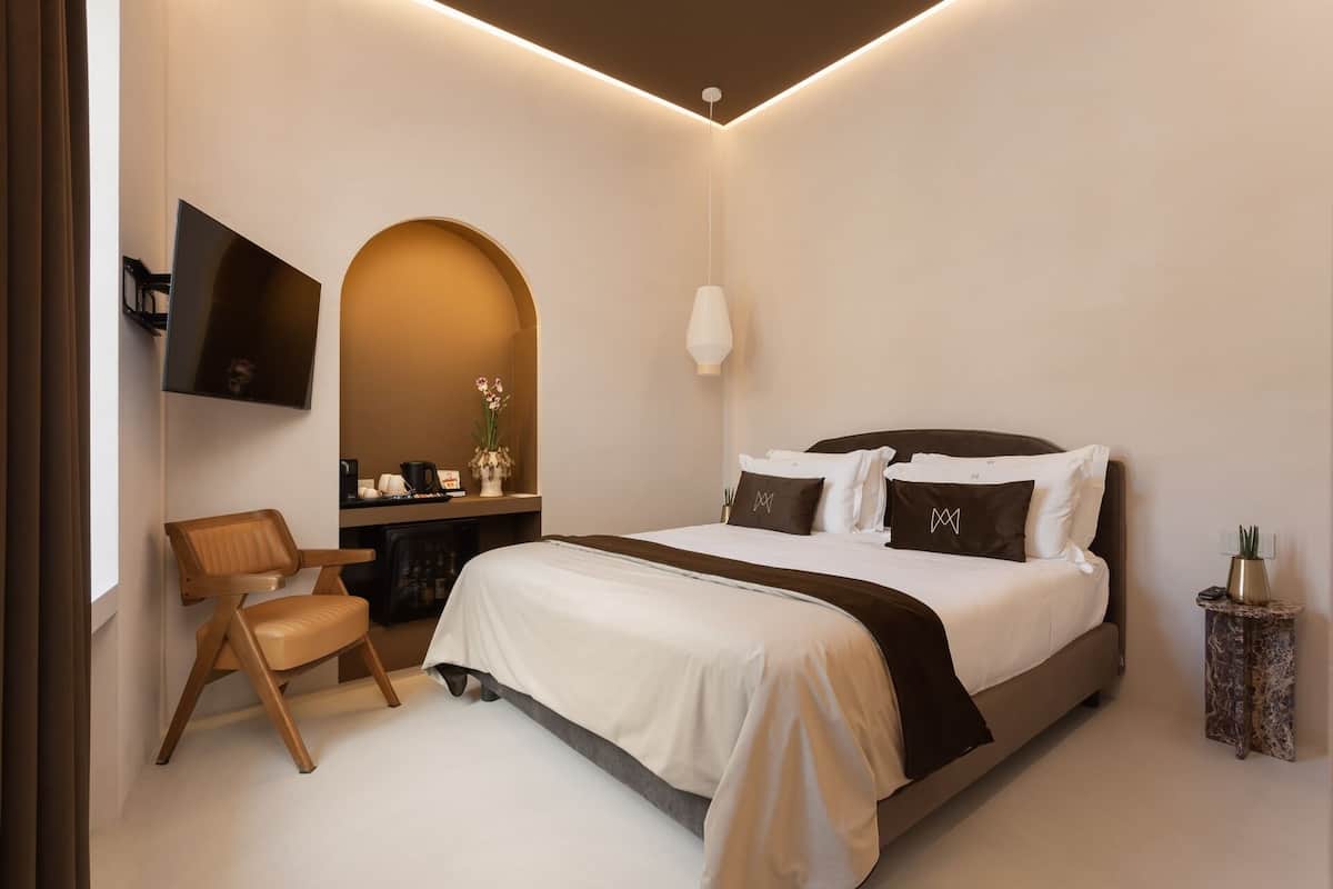 A modern hotel room with a bed, a TV, a desk, and a chair.