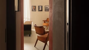 A hallway with a statue, a bed, a chair, and framed pictures on the wall. - Demetra Luxury Suites (Naples)