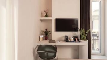 Una habitación moderna con escritorio, una silla, televisión, planta en maceta y ventana con cortinas.