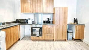 A compact kitchen with wooden cabinets, a dishwasher, a toaster, and a coffee maker. - Immaculate 2-bed Apartment in Birmingham (Birmingham)