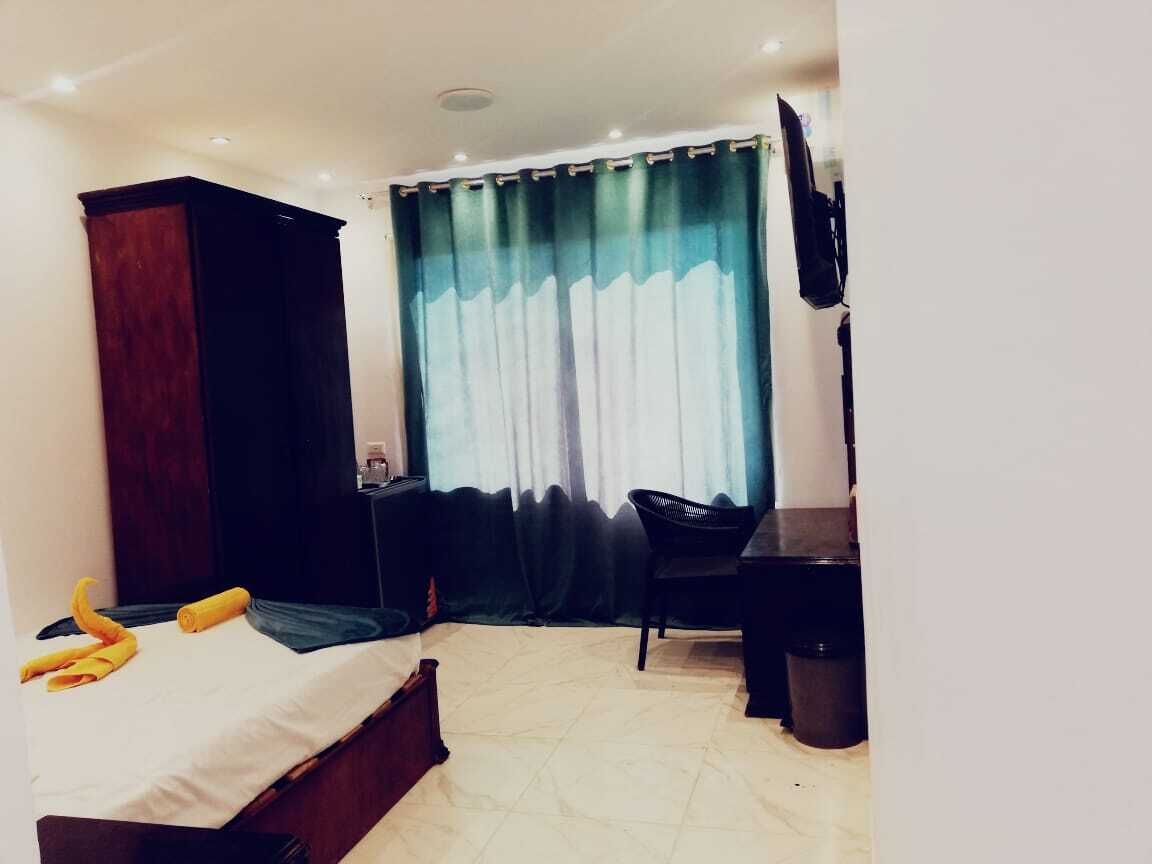 Una habitación de hotel con una cama, un escritorio, una silla, un armario y un televisor.