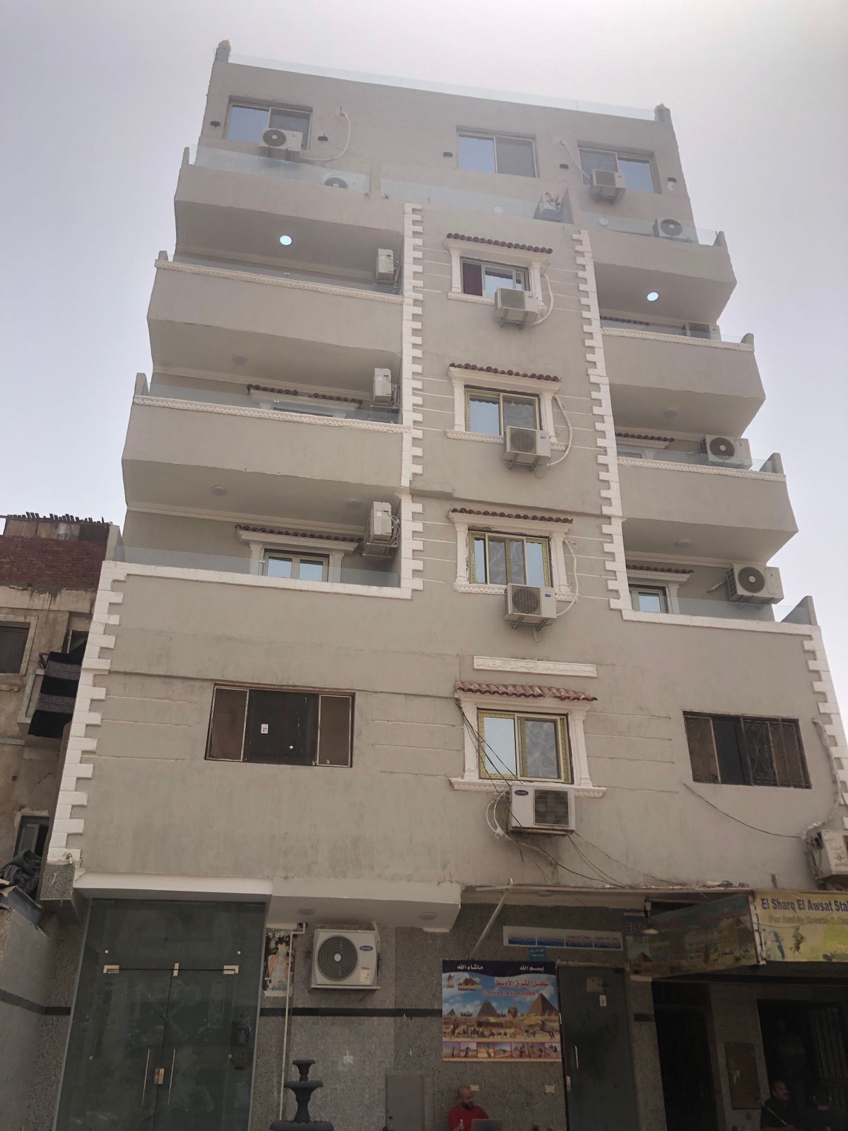 A multi-story building with balconies, air conditioning units, and a door with a security camera.