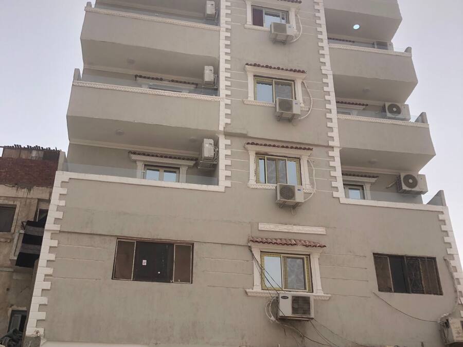 A multi-story building with balconies, air conditioning units, and a door with a security camera.