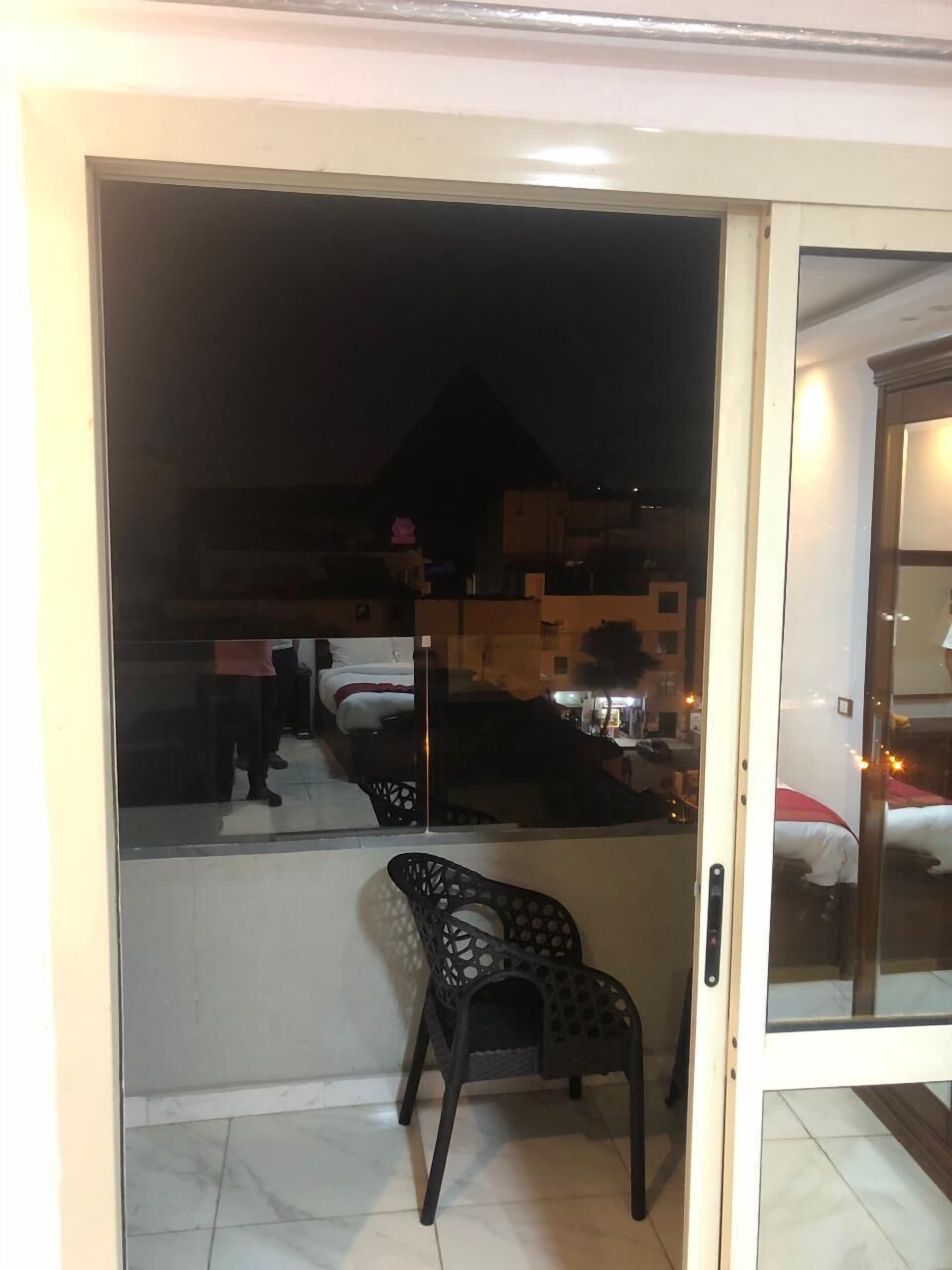 Una habitación con una cama, una silla y vistas al exterior de noche.