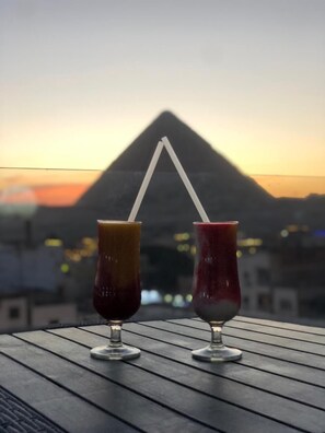 Two drinks with straws on a table with a view of a pyramid in the background.