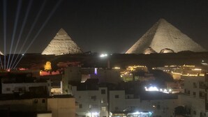 A nighttime view of the pyramids with city lights in the foreground. - Middle East Pyramids View (Giza)