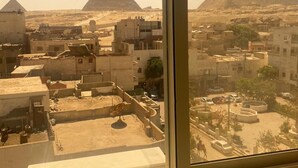 A view of the pyramids from inside a building, with buildings and streets in the foreground. - Middle East Pyramids View (Giza)
