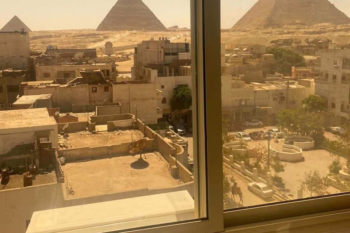 Vista das pirâmides vista de dentro de um edifício, com edifícios e ruas em primeiro plano.