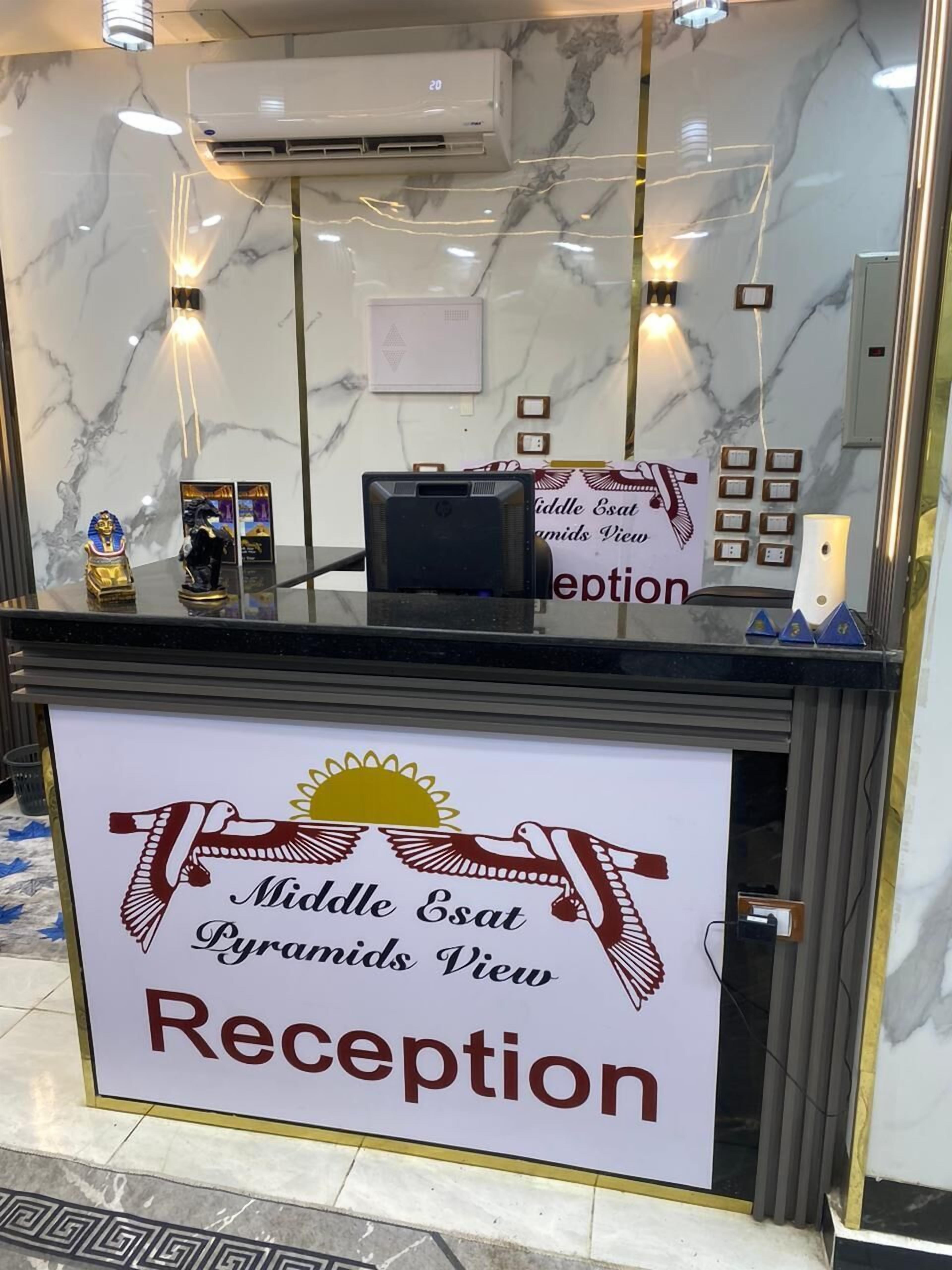 A reception desk with a marble wall background, a sign for 'Middle East Pyramids View Reception', and a small statue of an Egyptian figure.