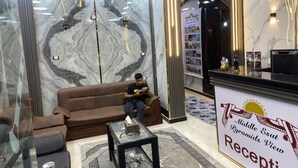 A reception area with a marble wall, a brown sofa, a glass table with a tissue box, and a sign reading "Middle Eastat Pyramids View Reception". - Middle East Pyramids View (Giza)