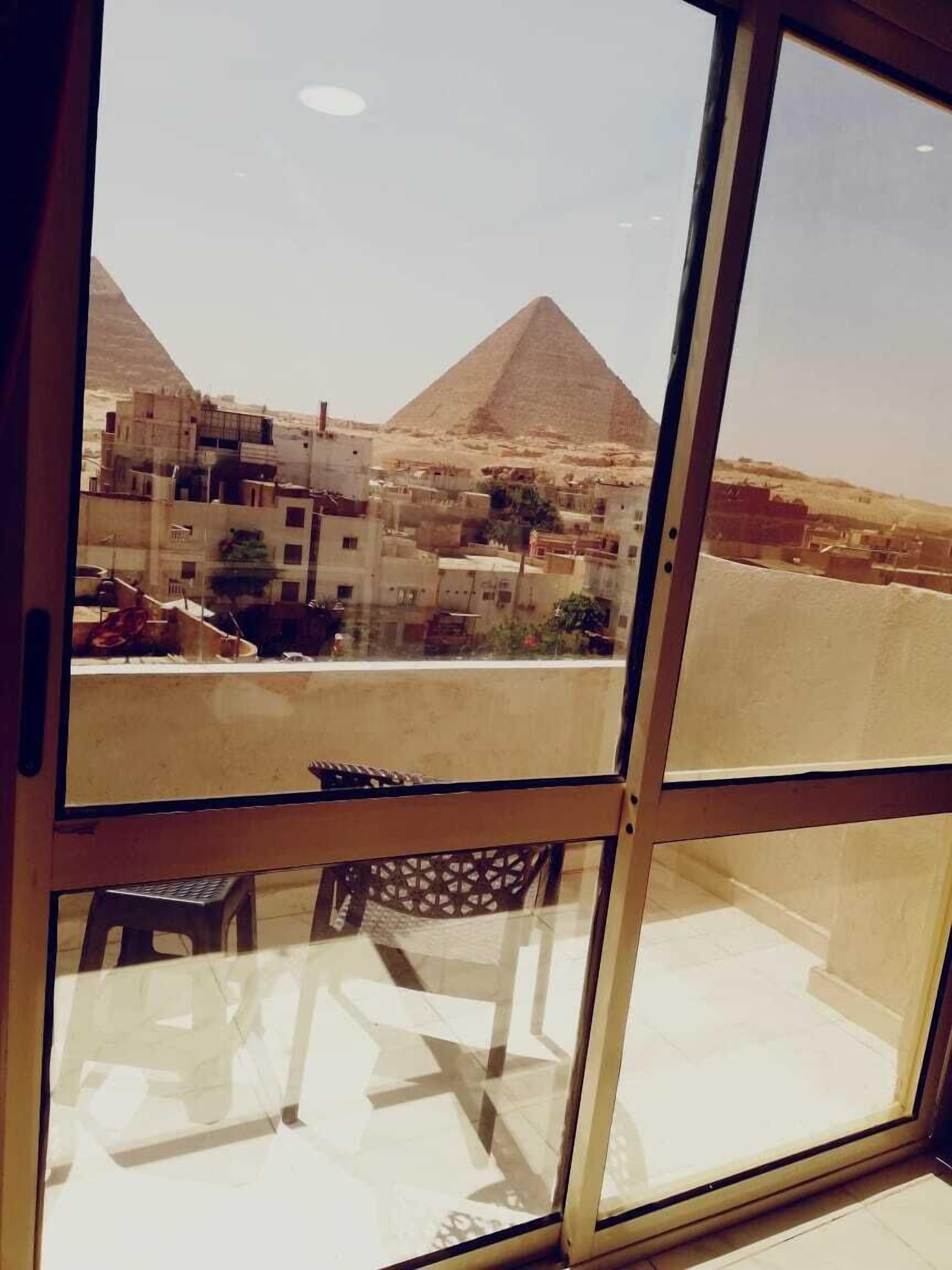 A view through a window of a building with a view of the pyramids in the background.