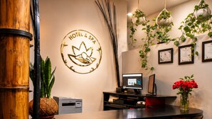A reception desk with a computer, framed certificates, and a logo for a hotel and spa. - Hotel Zensual (Bogotá)