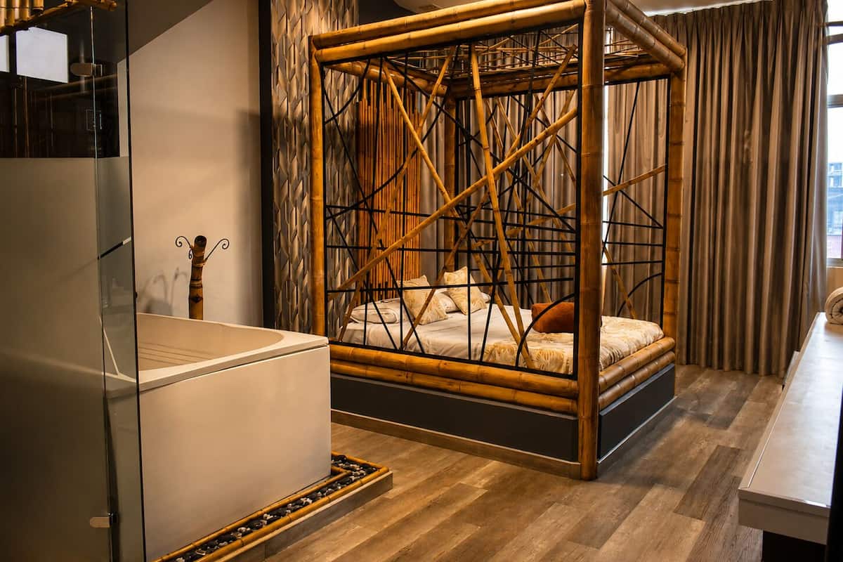 A room with a four-poster bed, a bathtub, and a glass shower enclosure.