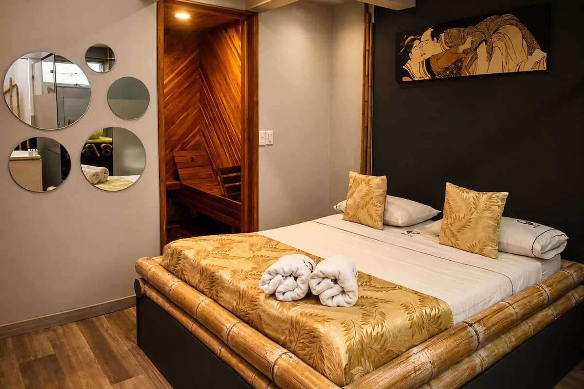 A bedroom with a bed, a wooden wardrobe, and a painting on the wall.