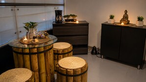 A room with a glass-top table, three bamboo stools, a dark wooden cabinet, and a statue. - Hotel Zensual (Bogotá)