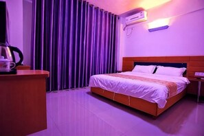 Una habitación de hotel con cama, escritorio y ventana con cortinas.