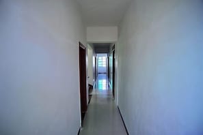 Un pasillo estrecho y bien iluminado con una puerta a la izquierda y un ventanal al final.