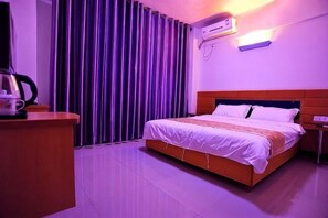 Una habitación de hotel con cama, escritorio y ventana con cortinas.