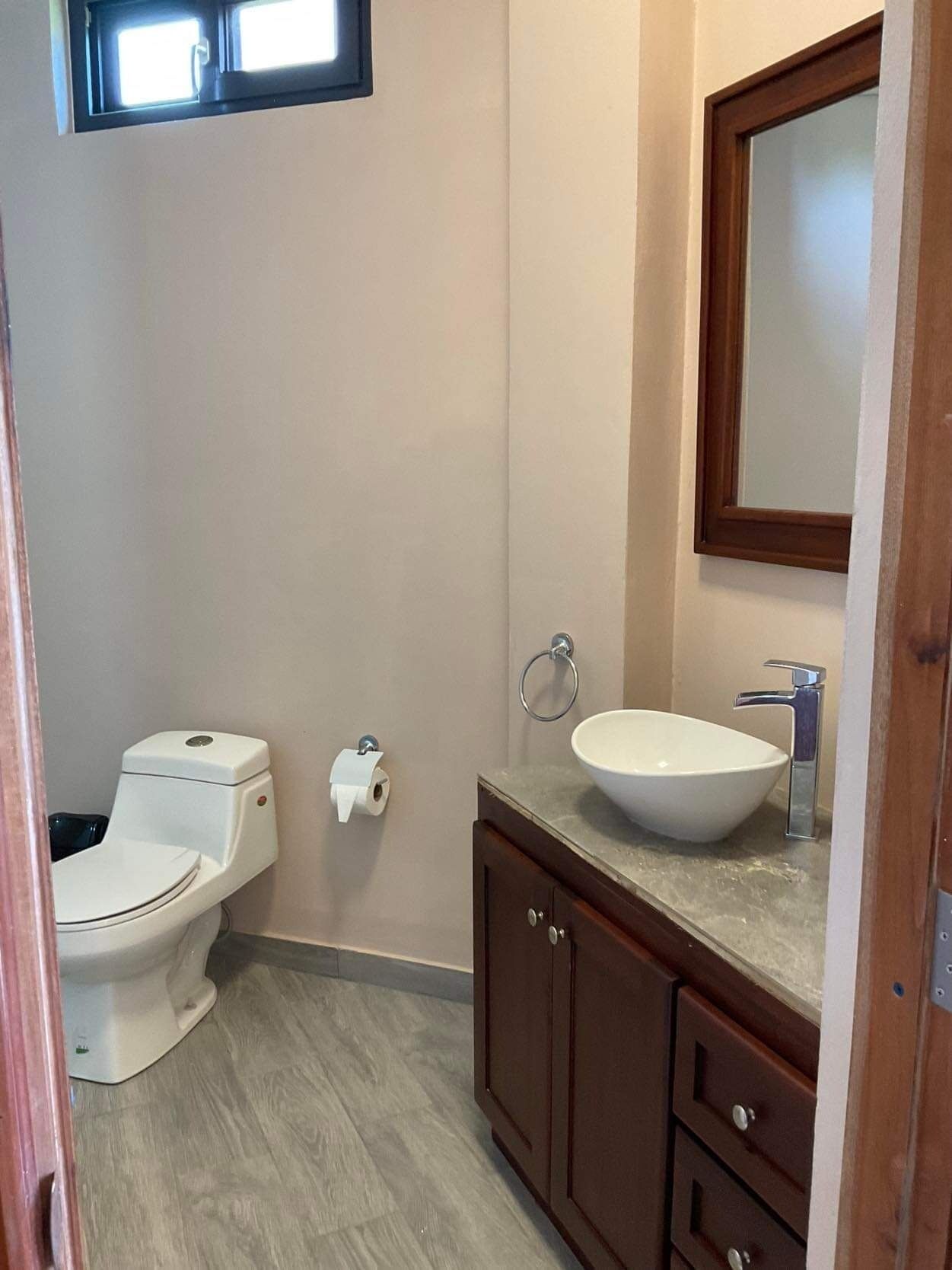 A bathroom with a toilet, sink, and mirror.