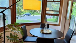 Un comedor con una mesa redonda, cuatro sillas negras y una lámpara colgante amarilla.