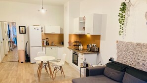 En kompakt bolig med et tekøkken, et spiseområde med et rundt bord og stole, samt en sofa.
