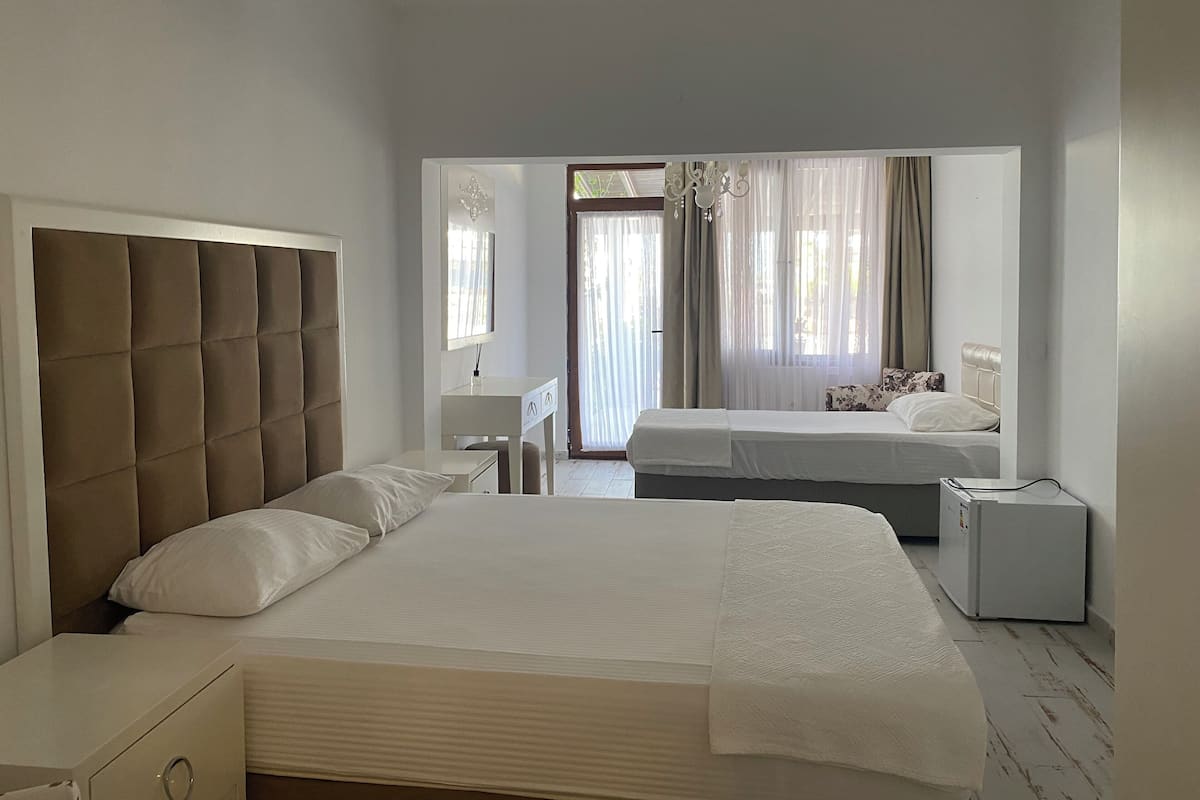 A hotel room with a large bed, a smaller bed, a desk, and a wardrobe.