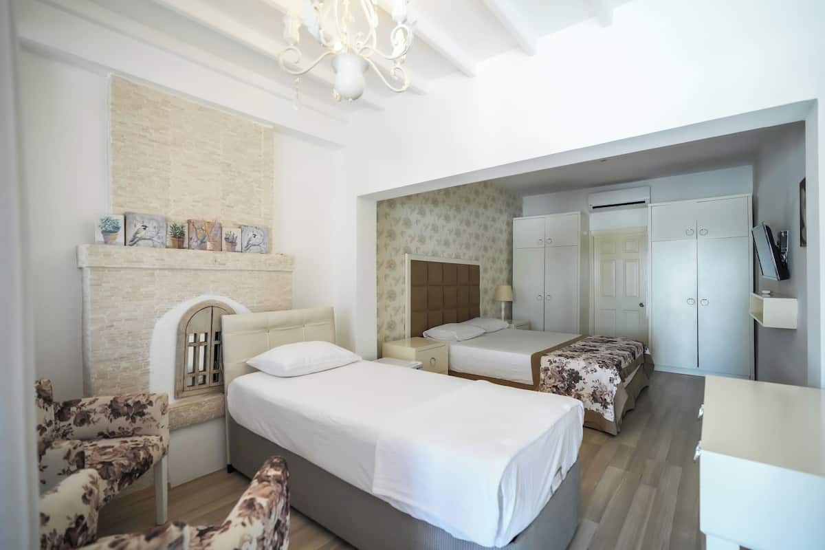 A bedroom with two beds, a chair, a wardrobe, and a small table.