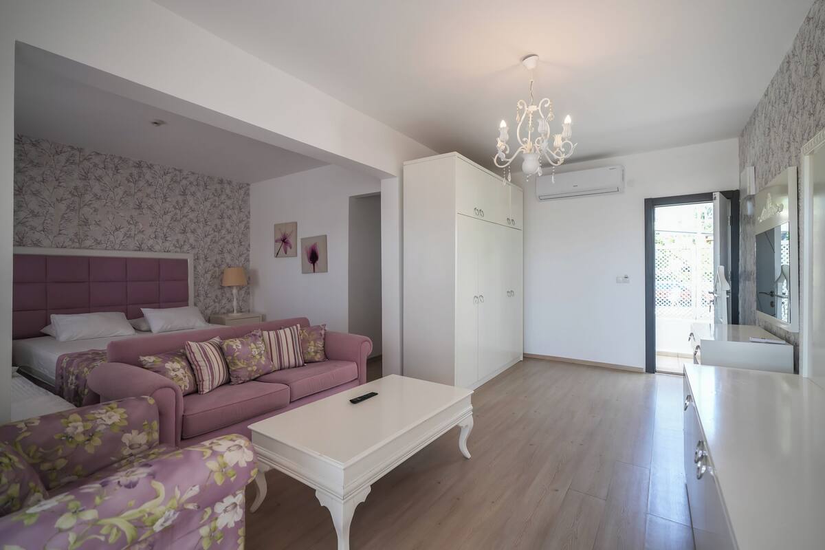 A modern living room with a pink sofa, a white coffee table, and a chandelier.