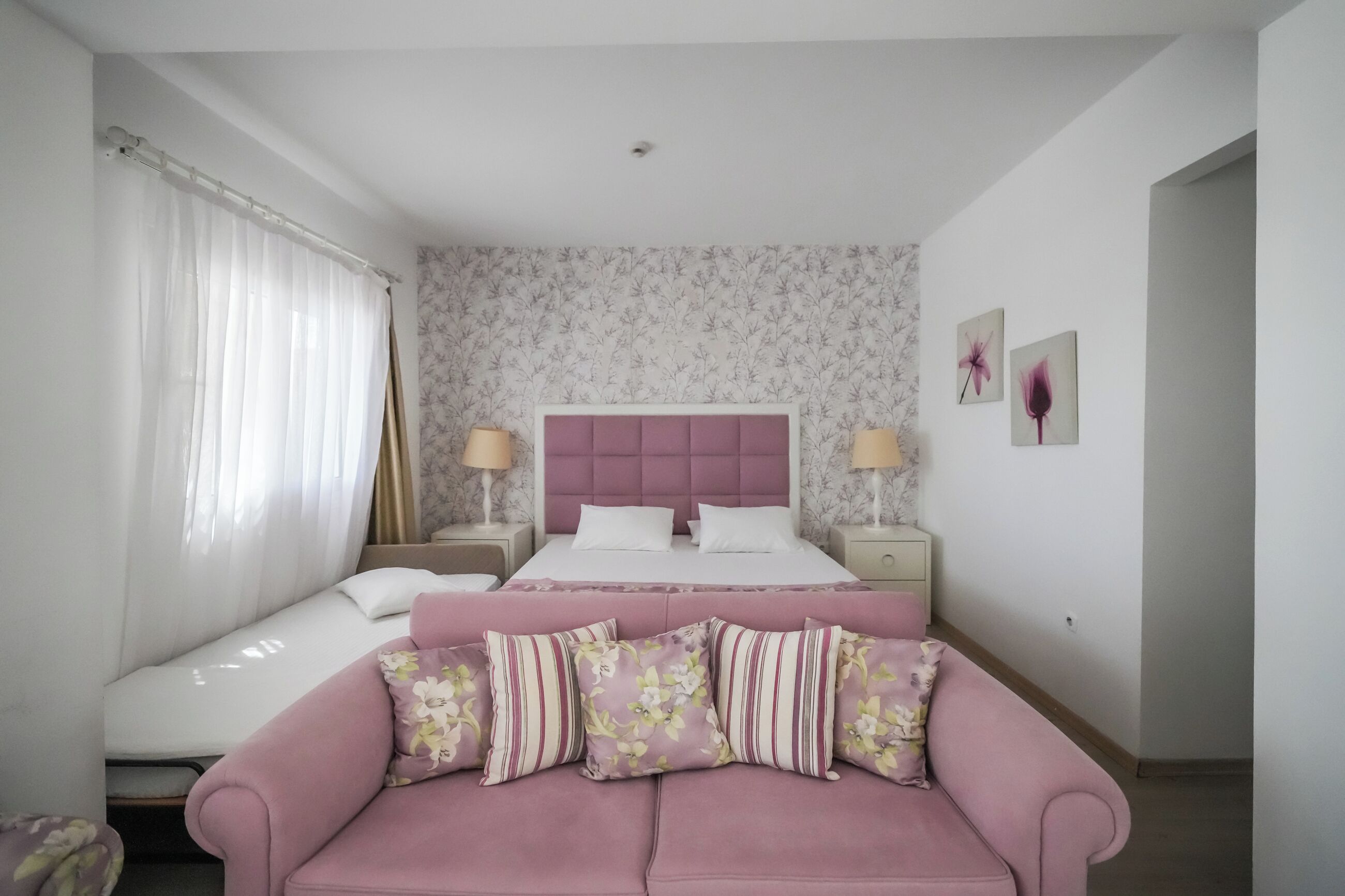 Un dormitorio con una cama, un sofá y una mesita de noche con lámpara.