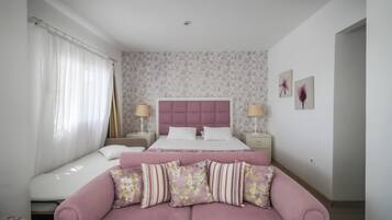 Un dormitorio con una cama, un sofá y una mesita de noche con lámpara.