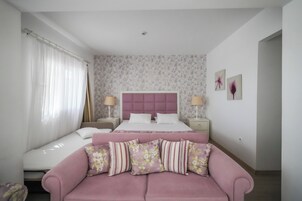 Un dormitorio con una cama, un sofá y una mesita de noche con lámpara.