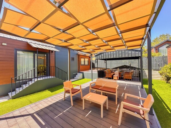 A covered outdoor patio with a wooden deck, outdoor furniture, and a grill area. - Baronet Tiny House Otel (Yalova)