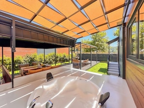 A modern outdoor hot tub area with a pergola overhead, a wooden deck, and a view of a backyard with a lawn and a wooden fence. - Baronet Tiny House Otel (Yalova)