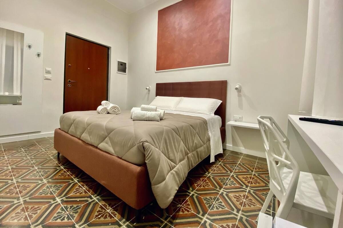 A hotel room with a bed, a desk, and a chair.