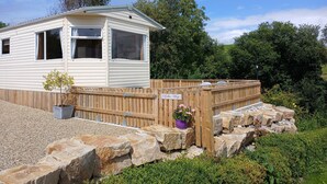A mobile home with a fenced yard, a small garden, and a sign indicating 'B&B Way'. - Comfortable Mobile Home in the Countryside (Birra)