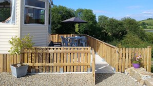 A mobile home with a deck, outdoor furniture, and a wooden fence. - Comfortable Mobile Home in the Countryside (Birra)