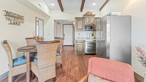 A kitchen with wooden cabinets, a stainless steel refrigerator, and a dining area with wicker chairs and a table.