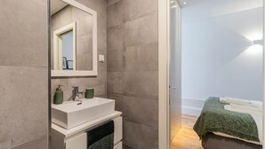 A modern bathroom with a white sink, green soap dispensers, and a mirror.
