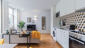 A modern kitchen with a built-in oven, a washing machine, and a dining area with a TV.
