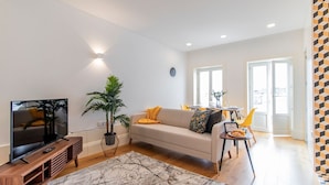 A modern living room with a flat-screen TV, a sofa, a coffee table, and a dining area with chairs and a table. - Rodrigues de Freitas 391 2J by LovelyStay (Porto)