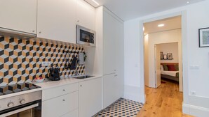 A compact kitchen with a microwave, stove, and modern tiled backsplash. - Rodrigues de Freitas 391 2J by LovelyStay (Porto)