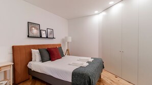 A modern bedroom with a bed, a bedside table, a lamp, and a wardrobe. - Rodrigues de Freitas 391 2J by LovelyStay (Porto)