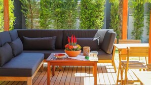 A wooden deck with a dark-colored sofa and a small table. - Artof  Alaçatı (Çesme)