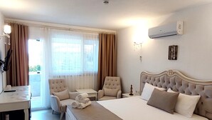 A hotel room with a large bed, a desk, a chair, and a small table. - Artof  Alaçatı (Çesme)