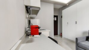 A modern kitchen with a red appliance, a white countertop, and a black chair. - Pretty Petitie Fully Equipped City Center Studio (Thessaloniki)