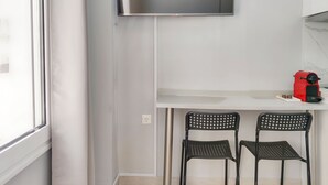 A room with a TV mounted on the wall, a red coffee machine, and two black chairs under a white desk. - Pretty Petitie Fully Equipped City Center Studio (Thessaloniki)