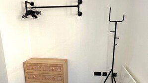 Une chambre à coucher avec une commode en bois, un porte-manteau et un radiateur.