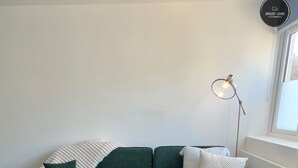 Un salon moderne avec un canapé d’angle, une petite table ronde et un lampadaire.